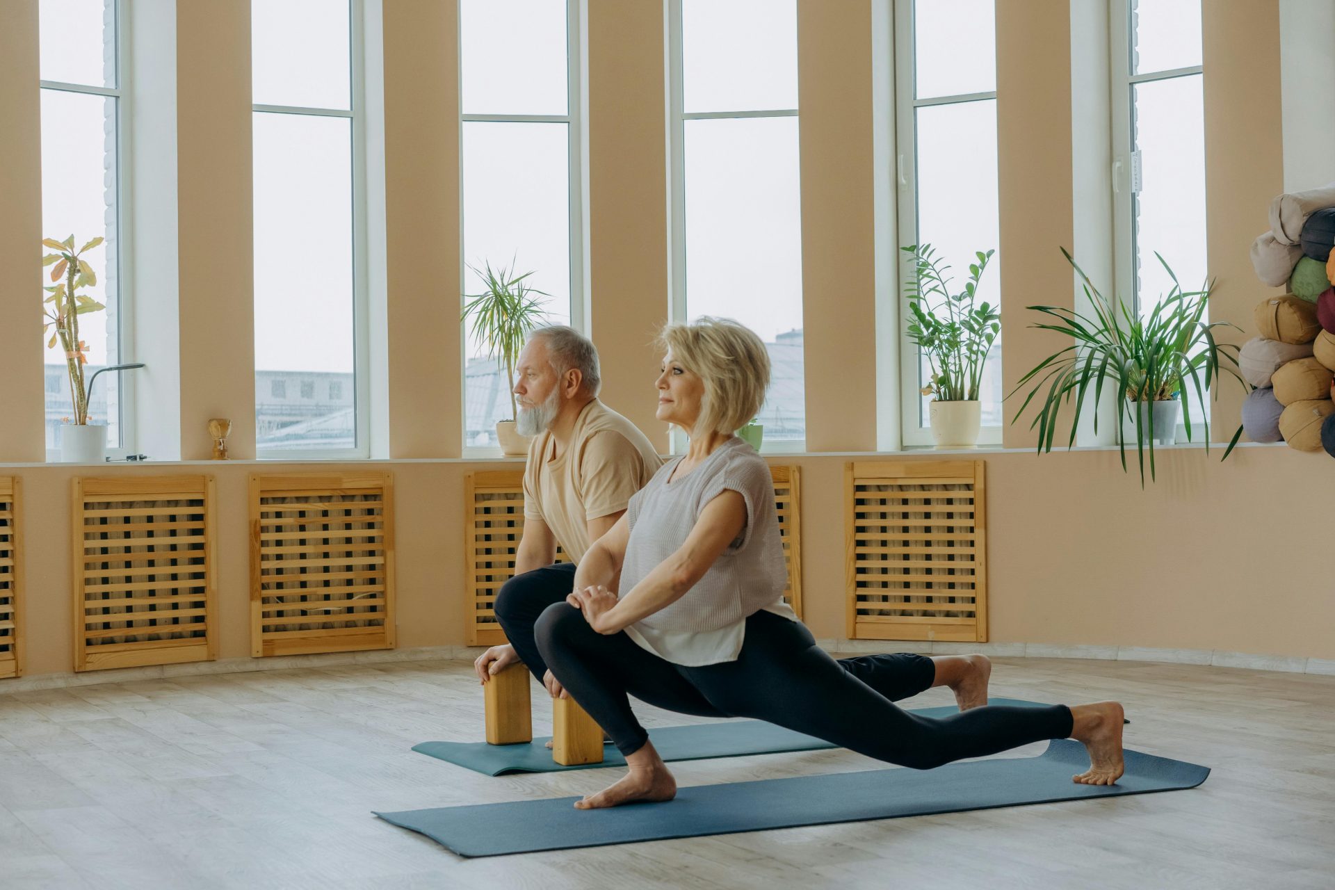 Ein älteres Paar praktiziert drinnen Yoga und konzentriert sich dabei auf einen gesunden Lebensstil und Flexibilität.